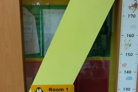 Classroom "Room 1" door, with a yellow accent stripe and a penguin nameplate