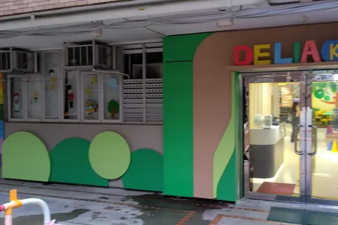 The school's entrance facade in daylight, with a green tree mural and a rainbow welcome sign